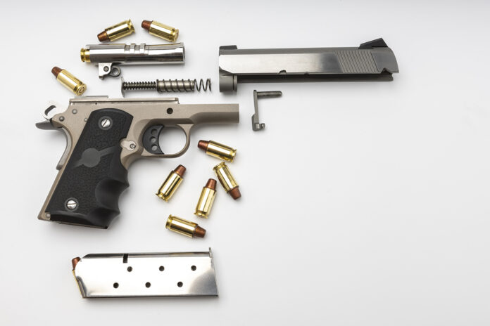 Parts of 1911 gun model and .45 bullets on white background